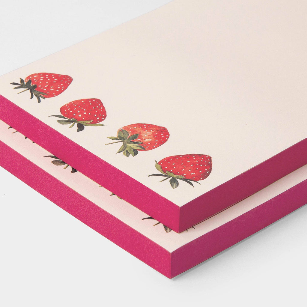 A stack of notepads with a light pink cover decorated with illustrations of red strawberries, and bright pink edges, shown on a clean white background.