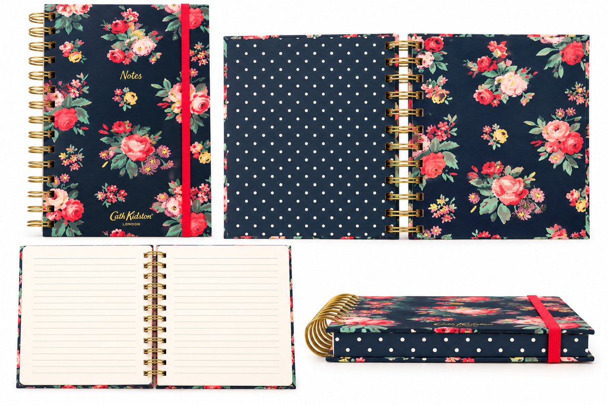 A floral and polka-dot spiral notebook shown in multiple views: closed with gold wire binding and a red elastic band, open with lined pages, and a back cover view. The cover features navy backgrounds with red and pink floral prints, white polka dots, and green leaves.
