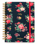 A spiral-bound notebook by Cath Kidston London with a navy blue cover decorated with a vibrant floral pattern of pink, red, and yellow roses with green leaves. It features a red elastic closure band and gold wire binding.