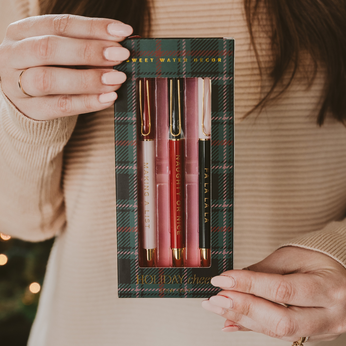 Person holding a set of pens in a plaid box with a blurred background